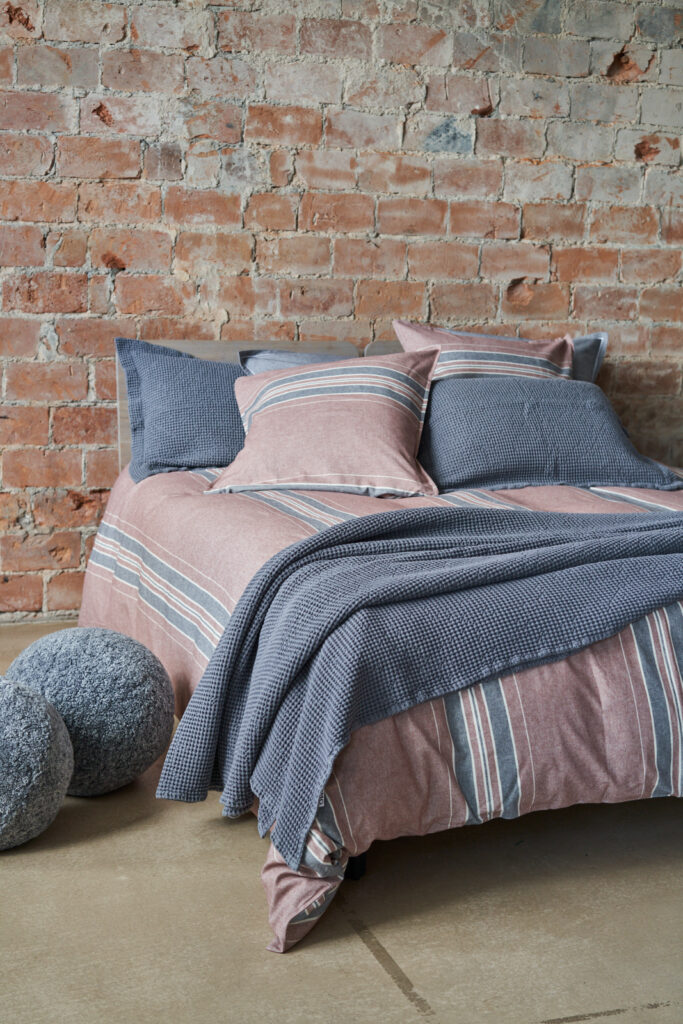 Een flanellen dekbedovertrek met verticale strepen ligt op een lits-jumeaux bed.